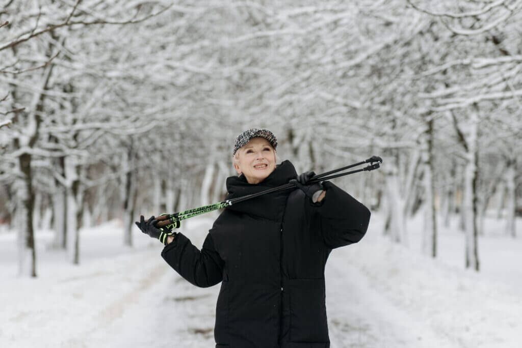 A picture of a senior standing in snowy woods for the Winter Wellness for Seniors article.